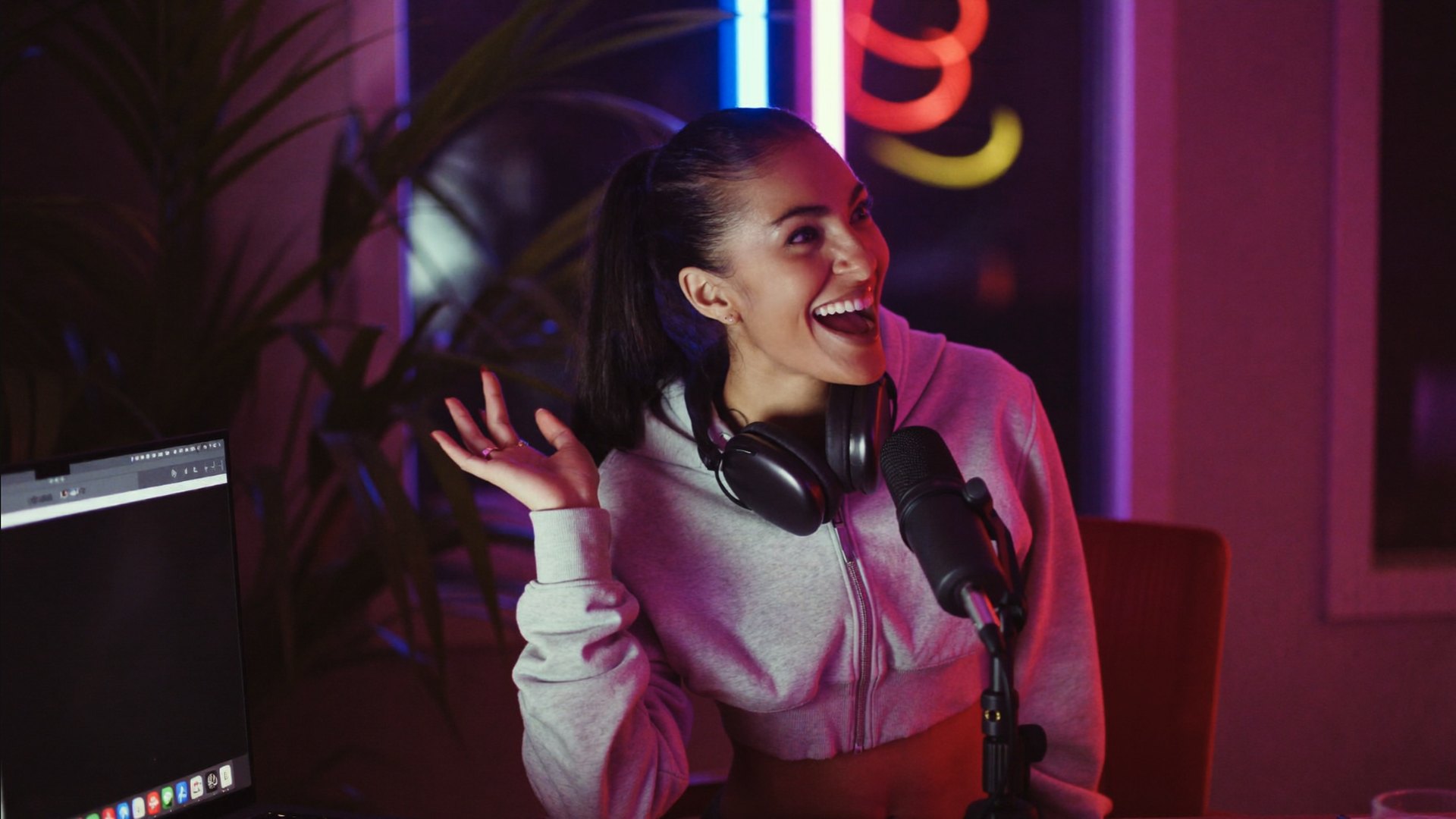 A content creator laughing at a neon-lit streaming desk